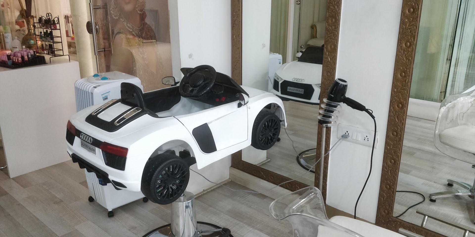 The kids' haircut chair at STUDIO@11: a white toy sports car parked in front of a full-length salon mirror.