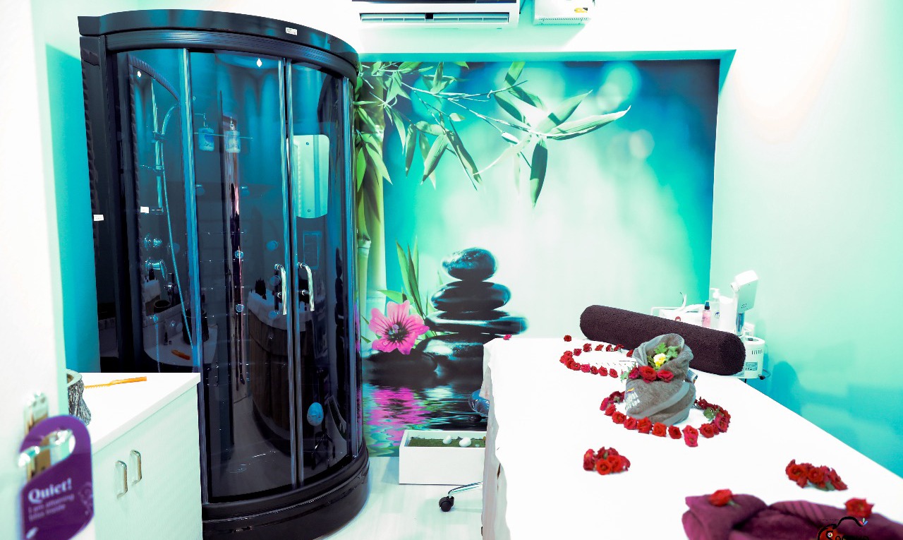 The spa room at STUDIO@11: steam cabin, massage table with rolled towels, stones and flower petals.